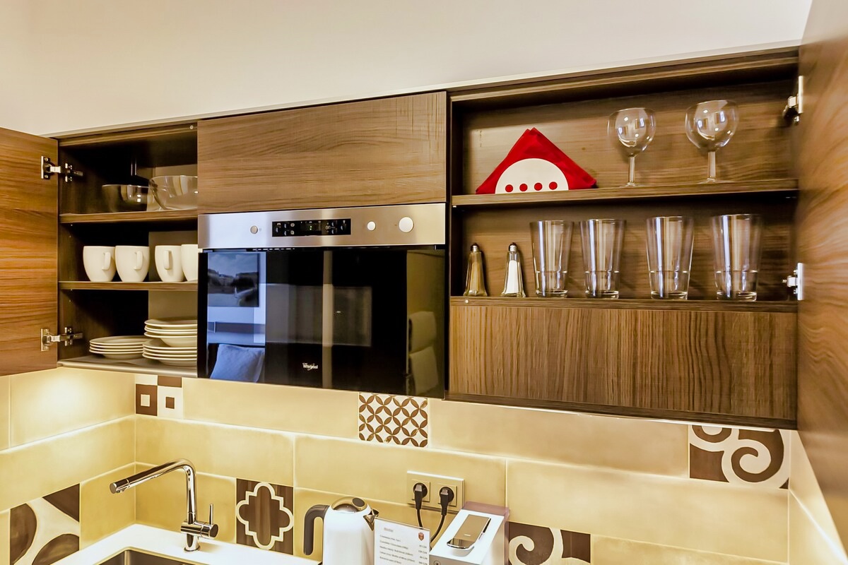 Sleek and stylish kitchen at Aparthotel Vinohradsky Dum featuring modern appliances and glassware. Hotel Prague.