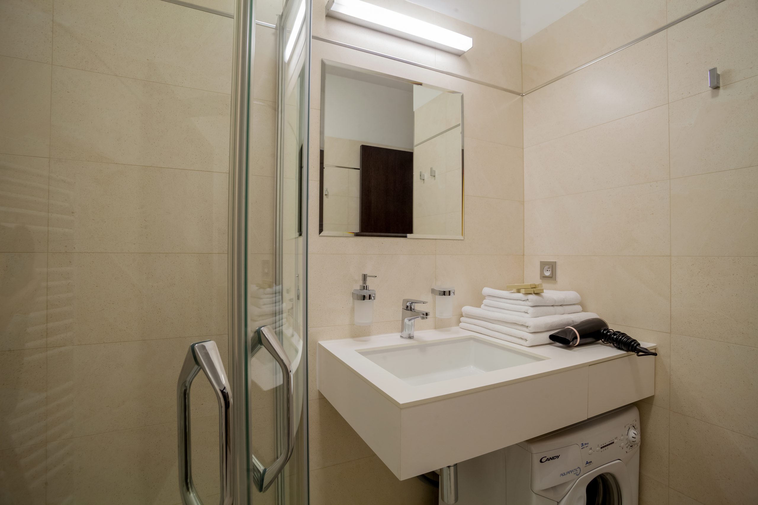 Discover the perfect blend of comfort and functionality in our bathroom at Aparthotel Vinohradský dům Prague - complete with a shower, toilet, and washing machine.