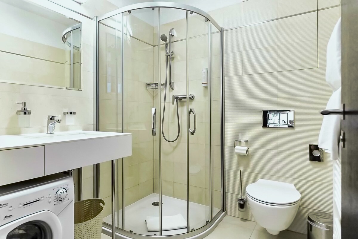Discover the perfect blend of comfort and functionality in our bathroom at Aparthotel Vinohradský dům Prague - complete with a shower, toilet, and washing machine.