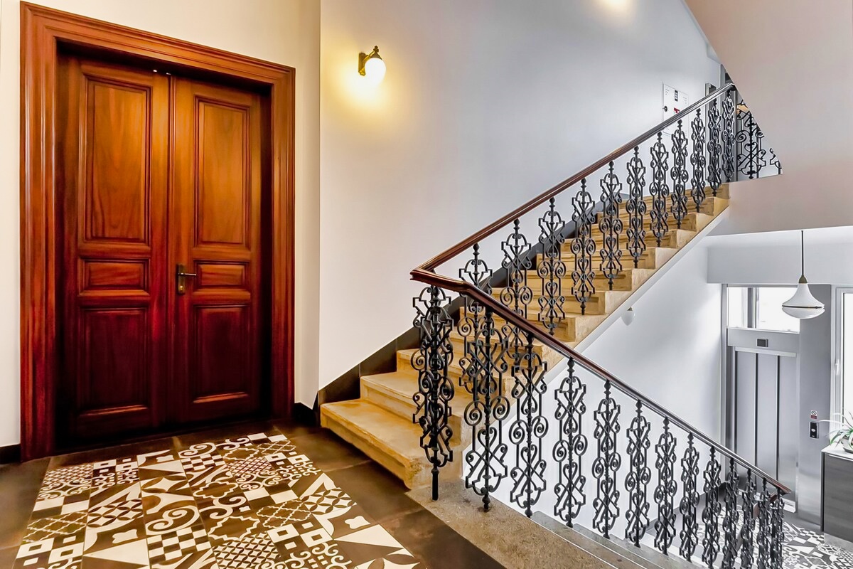 Luxurious marble staircase with intricate wrought iron balustrade inside Aparthotel Vinohradský Dům, inviting guests to the comfort and elegance of Prague's accommodations.
