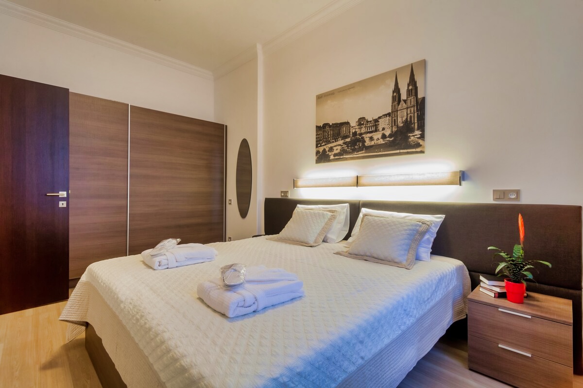 Book our Studio Suite Deluxe in Aparthotel Vinohradský dům Prague for a cozy bedroom with wooden furniture and a comfortable bed.