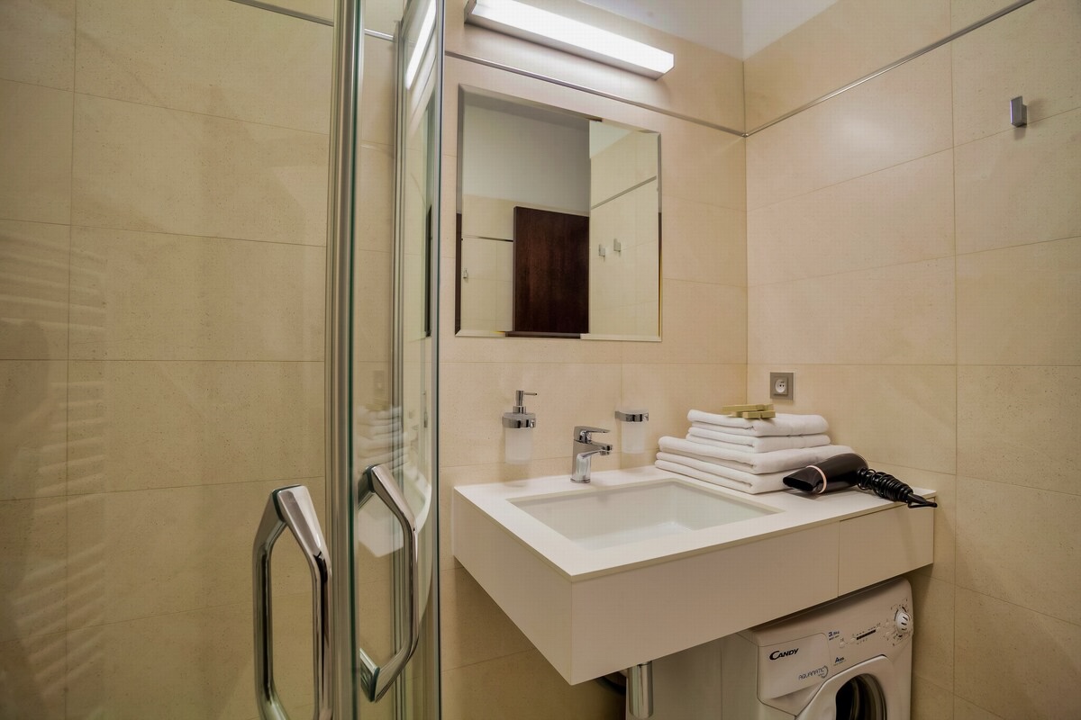 Discover the perfect blend of comfort and functionality in our bathroom at Aparthotel Vinohradský dům Prague - complete with a shower, toilet, and washing machine. Suite Superior.