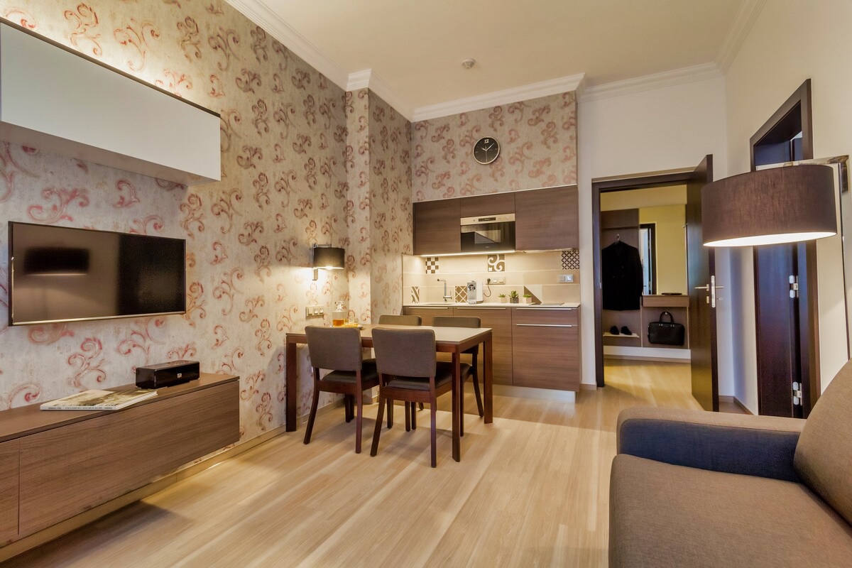 Discover the perfect blend of comfort and style in our Deluxe Suite at Apartment Hotel Vinohradský Dům. Reserve your stay and savor the ambiance of a small kitchen with a table and chairs
