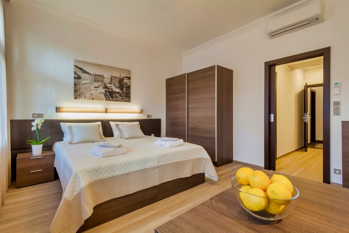 Step into relaxation at Aparthotel Vinohradský Dům's Studio Superior. Immerse yourself in a serene bedroom featuring a comfortable bed, table, and lamp